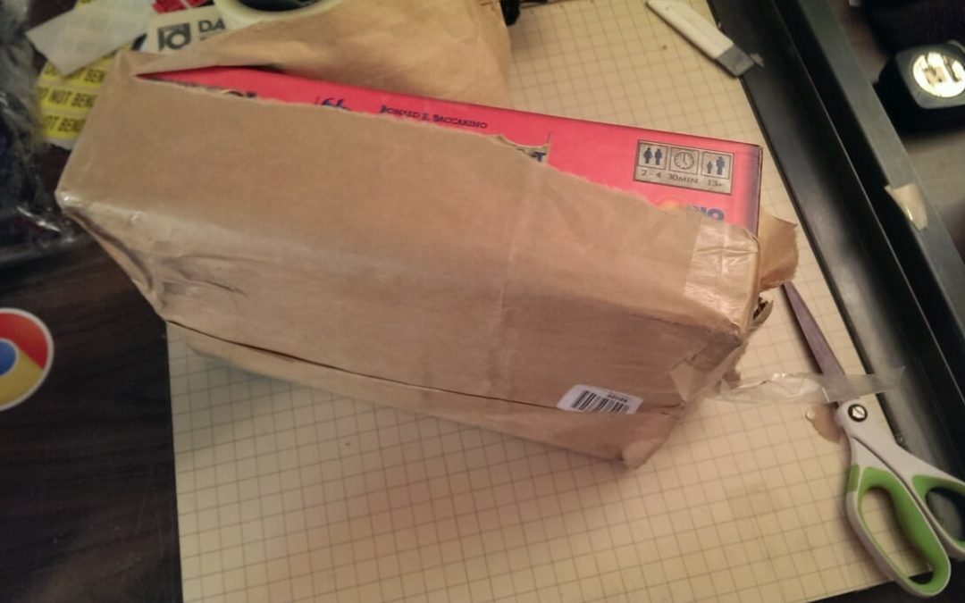 A board game box wrapped in brown paper for shipping